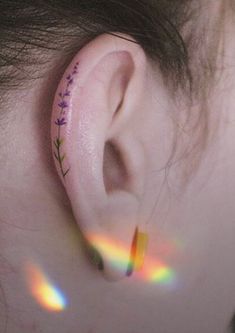 a person with a flower tattoo on their left side behind the ear is looking at something