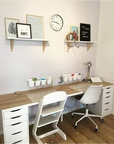 a white desk with two chairs and a clock on the wall above it in a room