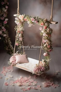 a swing bed with flowers on it in the middle of a room filled with petals