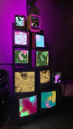 several televisions are stacked on top of each other in front of a purple wall