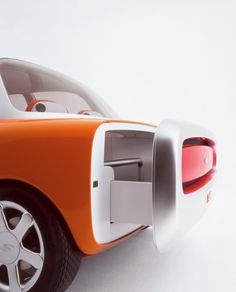 an orange and white toy car with wheels on it's rim, sitting in front of a white background