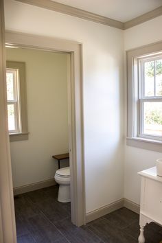 a white toilet sitting next to a window in a bathroom