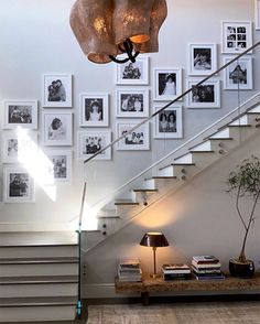 a staircase with pictures on the wall and a table under it next to a lamp