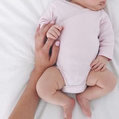 a woman holding a baby on top of a bed