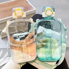 two clear bottles with yellow handles sitting on top of a table next to each other