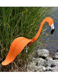 an orange flamingo standing next to some water