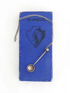 a blue book with a metal ball on the cover and a chain attached to it