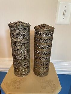 two metal vases sitting on top of a table