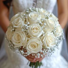 a bride holding a bouquet of white roses