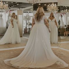 a woman standing in front of a mirror wearing a wedding dress