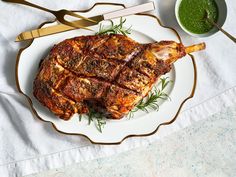 a large piece of meat on a plate next to a bowl of pesto sauce