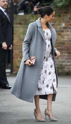 a woman in a dress and coat walking down the street