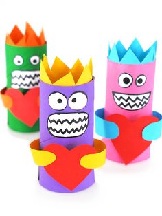 three different colored paper crafts with faces and mouths on them, one in the shape of a heart