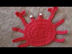 a red crocheted object with two white buttons on it's end and the top part of its head