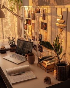 an open laptop computer sitting on top of a desk next to a potted plant