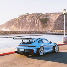 a blue sports car parked next to the ocean