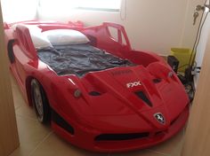 a red sports car bed in the corner of a room