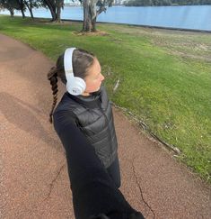 a woman with headphones on taking a selfie in front of a lake and trees