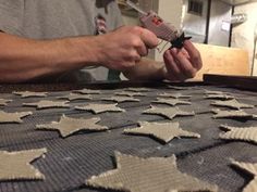 a man is working on an intricately designed tablecloth with star cut outs in the middle