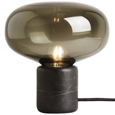 a black table lamp with a glass ball on it's base and a cord plugged in