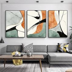 three abstract paintings hang on the wall above a couch in a living room with a coffee table