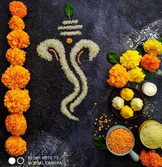 an image of ganeshi made out of flowers and rice on a black surface