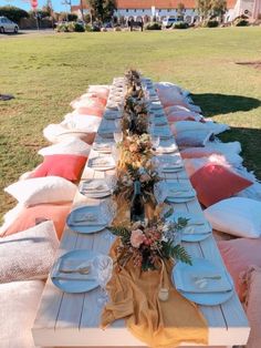 a long table is set up with plates and place settings for an outdoor dinner party