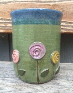 a close up of a ceramic cup on a wooden table near a fence and wood planks