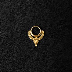 a gold nose ring sitting on top of a black leather surface