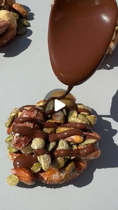 chocolate being drizzled on top of a pile of nuts