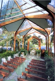 the inside of a building with wooden benches and plants in pots on either side of the walkway