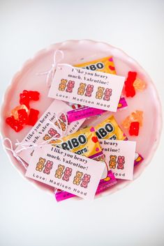 small candy bars with gummy bears in them on a pink plate and white background