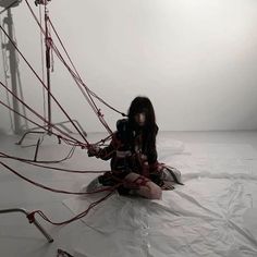 a woman sitting on the ground surrounded by wires