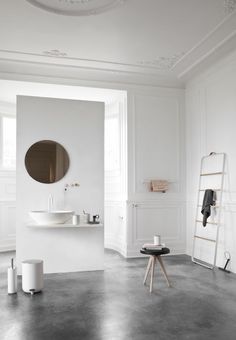 a bathroom with white walls and black accessories on the floor, along with a round mirror