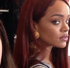 a close up of a person with long red hair and gold earring earrings on