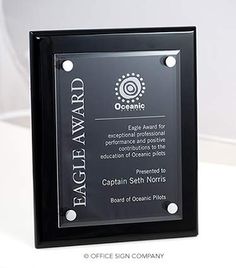 an award plaque is placed on top of a white table with a black frame and silver accents