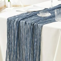 the table is set with silverware and glasses on it, along with a blue striped table runner