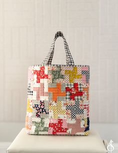 a multicolored patchwork bag sitting on top of a white cushion next to a wall