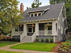 a small gray and white house with porches on the second floor, grass in front