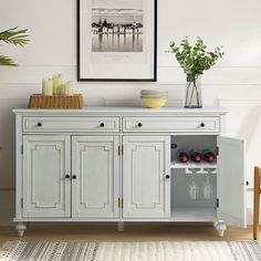 a white cabinet with two wine glasses on it and a vase filled with flowers next to it