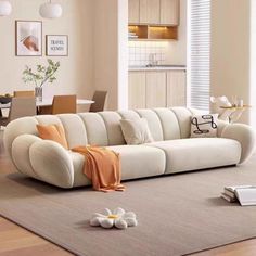 a white couch sitting on top of a wooden floor next to a table and chairs