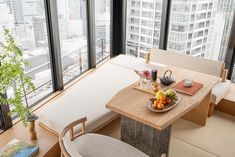 a small table with fruit on it in front of large window overlooking cityscape