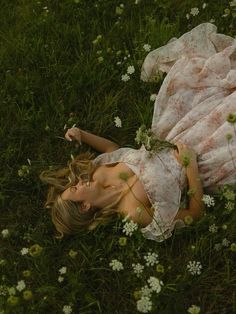 a woman laying on the grass in a dress