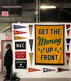 a man standing in front of a sign that says get the money up front and other signs