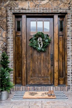 the front door is decorated with wreaths and doors are made from wood, which has been