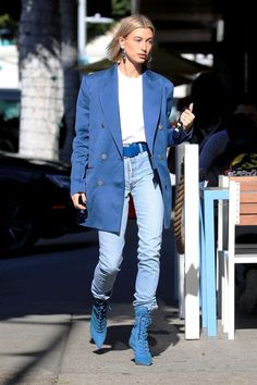 a woman in blue jacket and jeans walking down the street