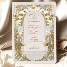 an ornate wedding card with flowers and leaves on the front, in gold foiled paper