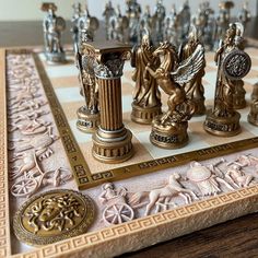 a chess board with gold and silver pieces on it's sides, including the statue of an angel