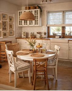 a kitchen table with four chairs around it and pictures hanging on the wall behind it