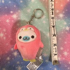 a pink stuffed animal keychain sitting next to a measuring ruler on a blanket